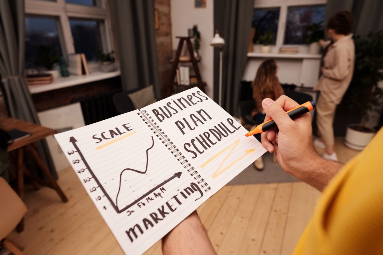 About Person holding a notebook with planning details and graph for business strategy indoors.