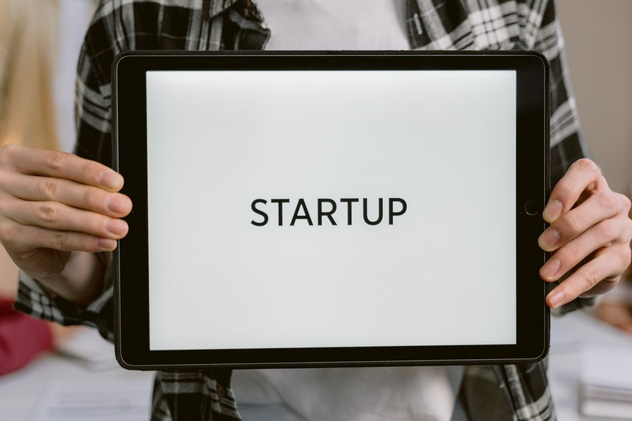 Services Person holding a digital tablet displaying the word 'STARTUP', representing new business concepts.