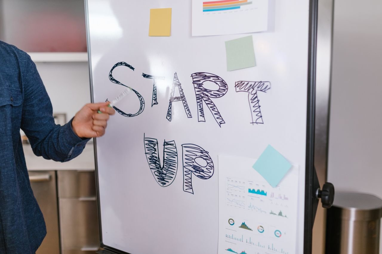 About A person presents a startup idea on a whiteboard in an office setting, emphasizing entrepreneurship.